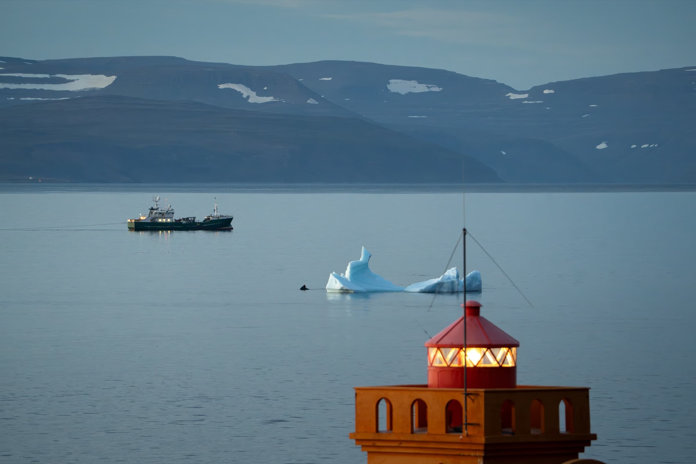 Rauður viti fyrir framan fjörð með ísjökum