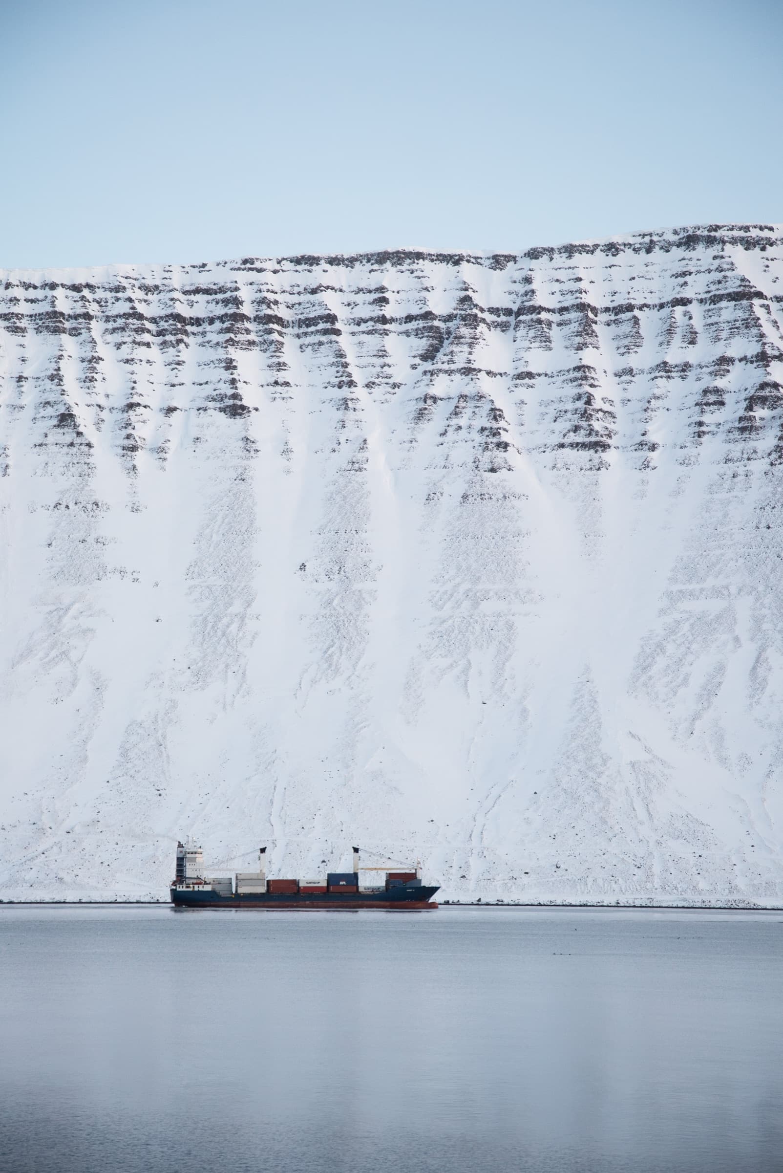 Snævi þakin fjallshlíð með lágum húsum við rætur hennar